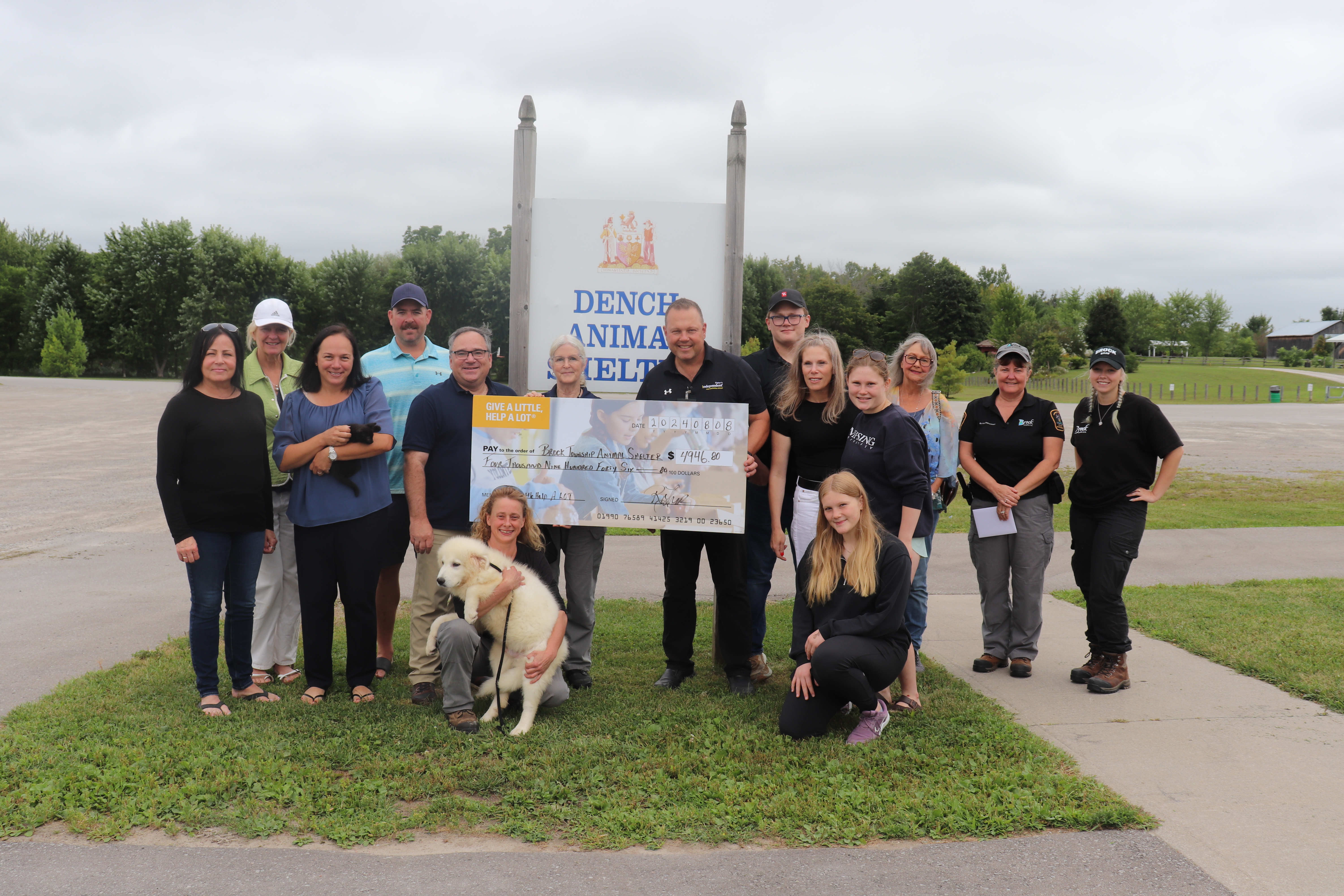 Picture of township staff, Council and Fisher family present a giant check out side of the animal shelter